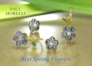 A pair of 18k yellow gold wild child flower earrings by jewelry designer Paul Morelli featuring blue sapphires with white diamond centers with green tsavorite garnet leaves 