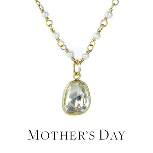 A wire wrapped, 18k yellow gold necklace with round, white pearls with a bezel set, faceted white sapphire pendant, handcrafted by jewelry designer Mallary Marks
