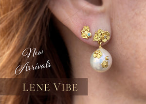 An 18k yellow gold stud earring with a carved flower and blue diamond paired with a white south sea pearl earring by jewelry designer Lene Vibe