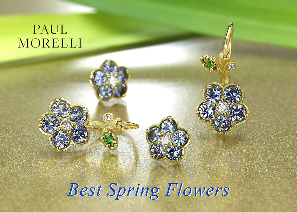 A pair of 18k yellow gold wild child flower earrings by jewelry designer Paul Morelli featuring blue sapphires with white diamond centers with green tsavorite garnet leaves 