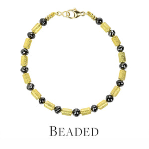 Beaded bracelet with gold and black beads on a white background