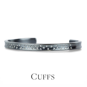 Silver cuff bracelet with small stones on a white background