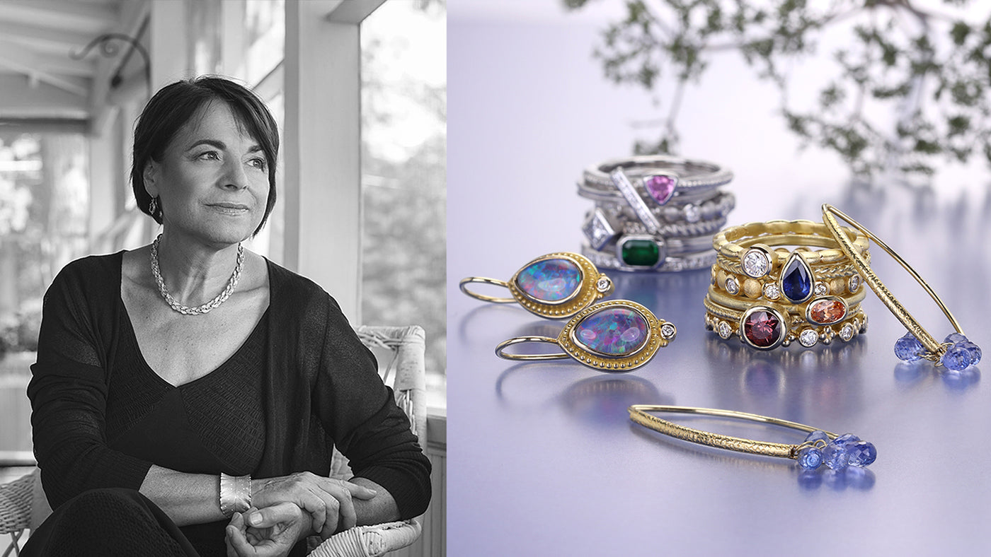 Woman wearing jewelry with a display of various rings and earrings on a table.