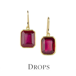 Gold earrings with red gemstones on a white background