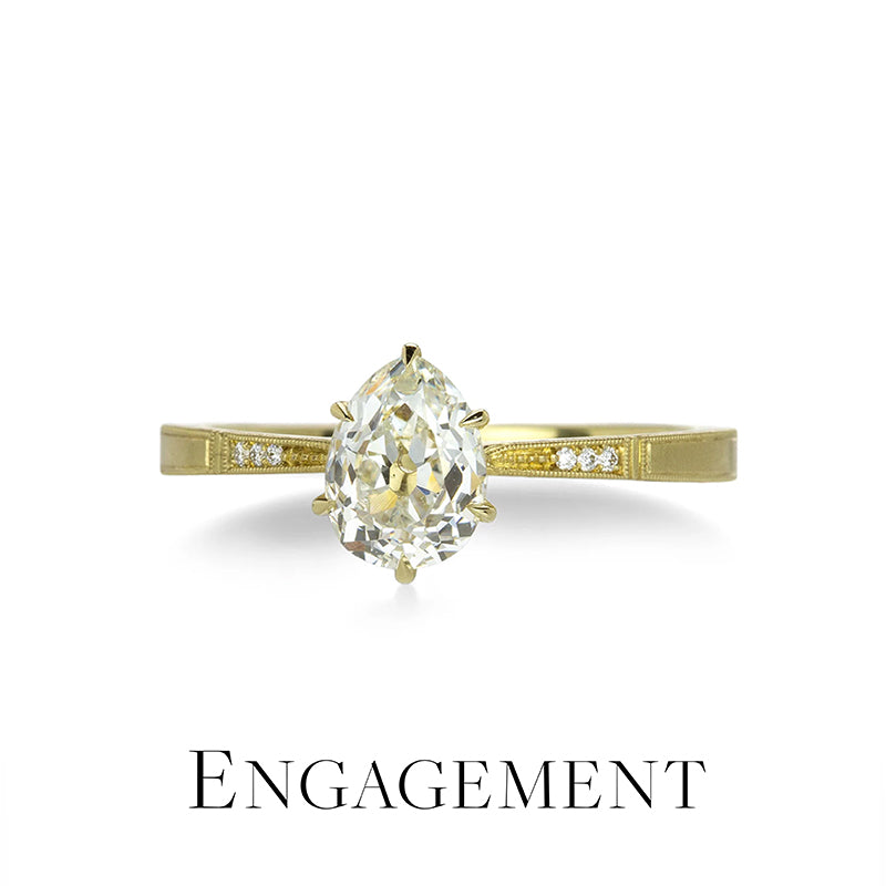 Gold engagement ring with a pear-shaped diamond on a white background