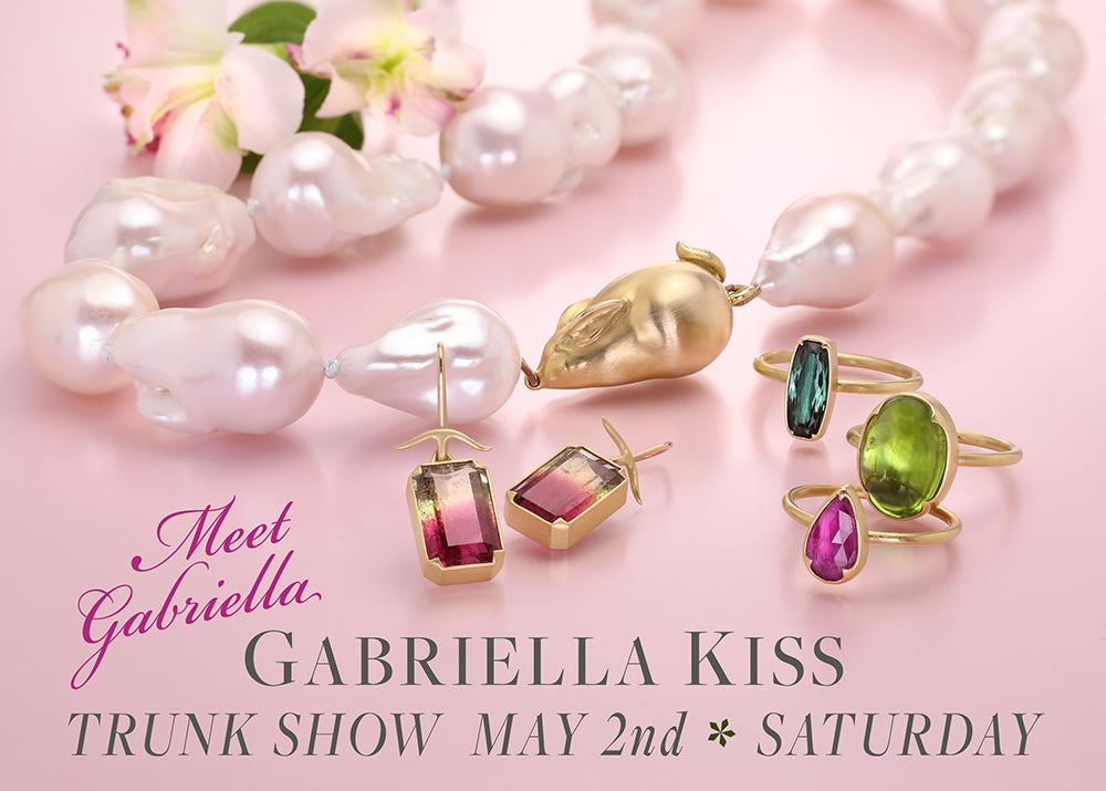 Jewelry display with pearls and gemstone rings on a pink background, featuring Gabriella Kiss jewelry.