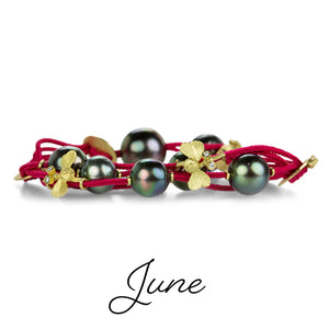 A multistrand red cord bracelet with dark gray Tahitian pearls, 18k yellow gold critters and gold accent beads. Handcrafted by jewelry designer Lene Vibe.