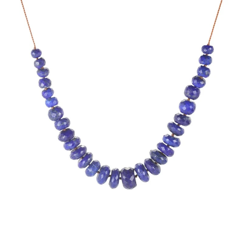 A beaded necklace made of faceted, irregular blue lapis lazuli stones strung on a thin copper-colored cord, shown against a plain white background.
