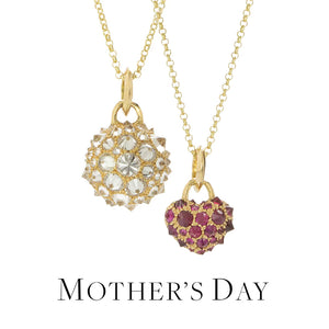 Two 18k yellow gold necklaces. On the left,  a delicate 18k yellow gold chain with a round ball pendant set with inverted white diamonds. On the right, a delicate 18k yellow gold chain with a heart shaped pendant set with inverted rubies. Handcrafted by jewelry designer Tamsin Rasor.