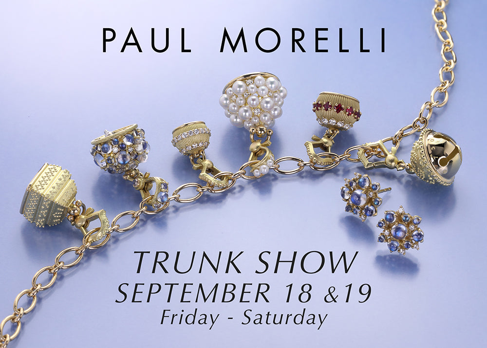 Promotional graphic for Paul Morelli jewelry featuring several gold-tone charm beads and matching chain links arranged on a pale lavender background, with text reading 'PAUL MORELLI' and 'TRUNK SHOW SEPTEMBER 18 &19 Friday - Saturday'.