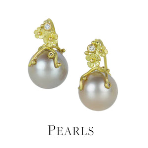 A pair of 18k yellow gold earrings with round, pale pink pearl drops and carved flower tops with bezel set white diamonds, handcrafted by jewelry designer Lene Vibe