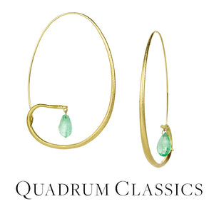 A pair of 18k yellow gold snake hoops with diamond eyes and faceted emerald briolettes hanging from their mouths. Handcrafted by jewelry designer Gabriella Kiss. 