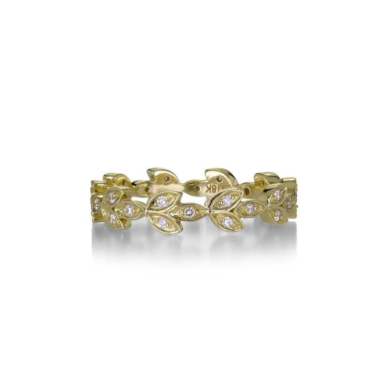A yellow gold leaf-patterned eternity band ring set with small clear stones, shown on a clean white background with a soft reflection.