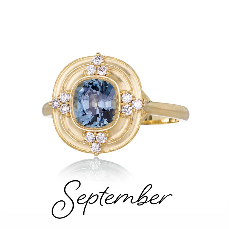 Gold ring with a blue gemstone and diamonds, labeled 'September', on a white background