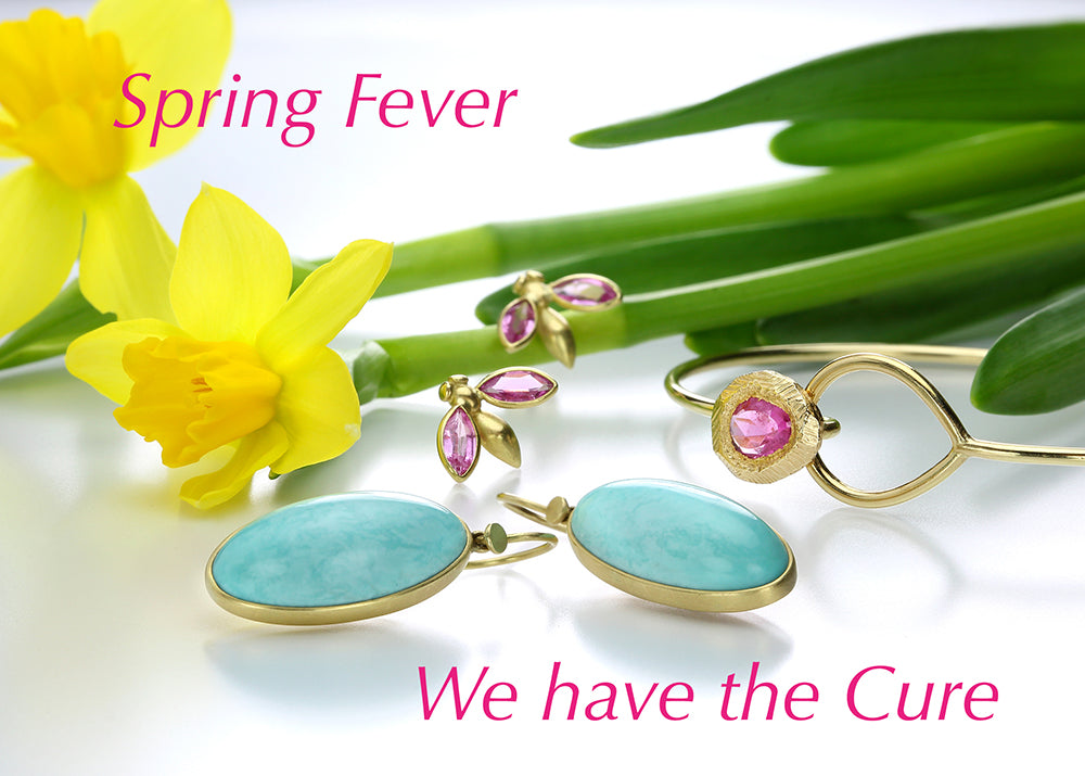 Bright yellow daffodils in the background, with a pair of oval, turquoise earrings by jewelry designer Lola Brooks, a pair of pink sapphire winged gem bug studs in 18k yellow gold by jewelry designer Gabriella Kiss and a delicate gold bangle with a hot pink sapphire by jewelry designer Page Sargisson