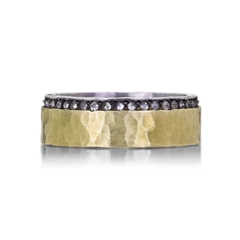 Ring with gold band and black and silver stone detailing on a white background