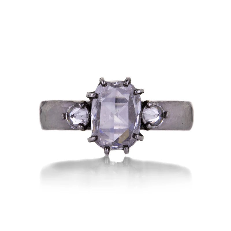 Silver ring with a central diamond and two smaller diamonds on a white background