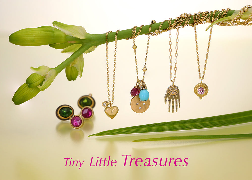 Jewelry including necklaces and earrings hanging from a branch with 'Tiny Little Treasures' text.