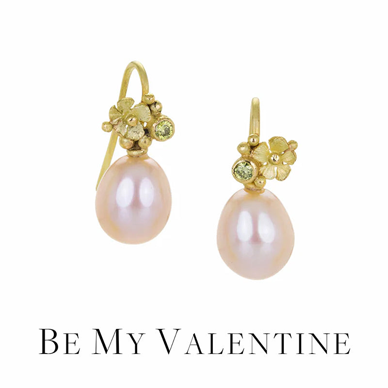 Pair of pearl earrings with gold and green accents on a white background, accompanied by 'Be My Valentine' text.